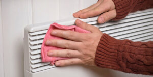 gros-plan-sur-des-mains-nettoyant-le-radiateur-electrique-avec-un-chiffon-microfibre gros plan sur des mains nettoyant le radiateur électrique avec un chiffon microfibre