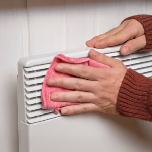 gros-plan-sur-des-mains-nettoyant-le-radiateur-electrique-avec-un-chiffon-microfibre-carre dépoussiérer le radiateur