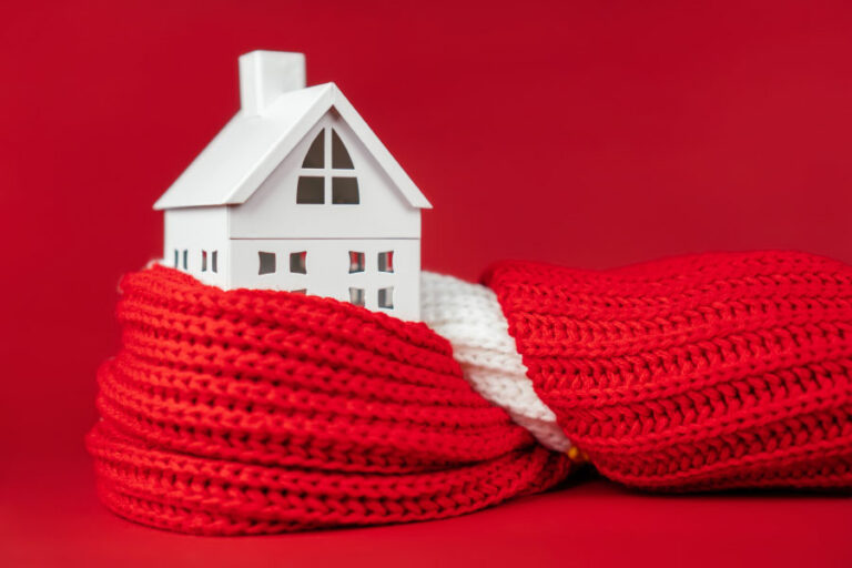 chauffer une maison symbolisé par une maquette de maison dans une écharpe en laine