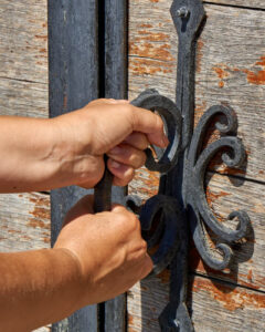 mains poussent fort pour ouvrir une vieille porte en bois bloquée