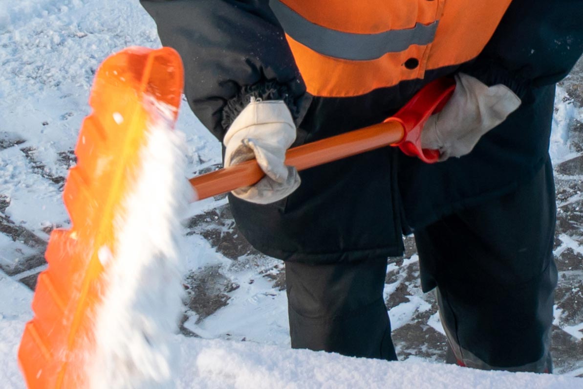 travailleur publique déblaye la neige avec une pelle et des gants de protection thermique