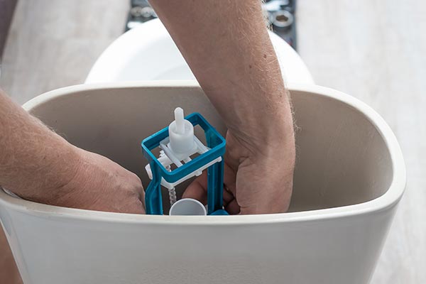 plombier règle la chasse d'eau dans les wc