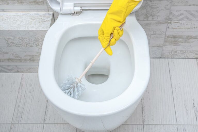 main gantée nettoie la cuvette des wc pour en enlever le calcaire