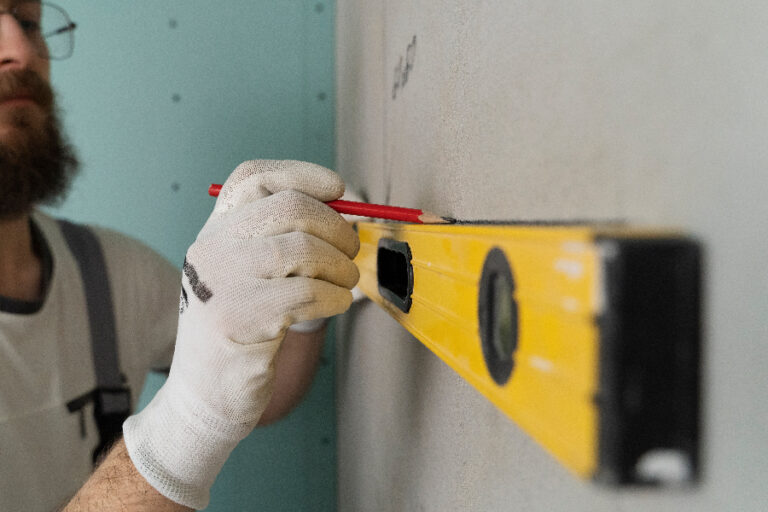 travailleur trace des repères sur le mur avant de poser le carrelage