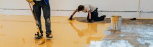 travailleur enduisant sol résine epoxy autonivelante dans atelier industriel