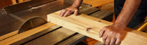 menuisier travaille le bois avec une scie sur table sans gants de protection