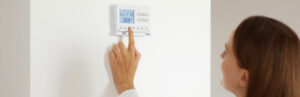 personne ajustant la temperature du thermostat en appuyant sur un bouton