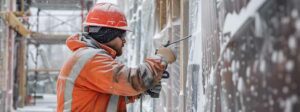 ouvrier du bâtiment sur le chantier de construction sous la neige porte une veste de protection contre le froid extrême