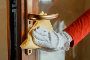 main gantée nettoie une poignée de porte en laiton avec un chiffon