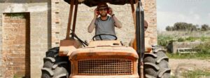 agriculteur sur son tracteur porte des epi casque auditif et lunettes solaires