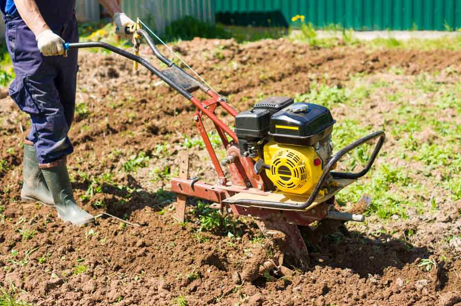 jardinier utilise motobineuse pour labourer la terre et cultiver son jardin