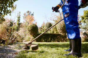 jardinier passe la débroussailleuse dans le jardin pour entretenir la pelouse