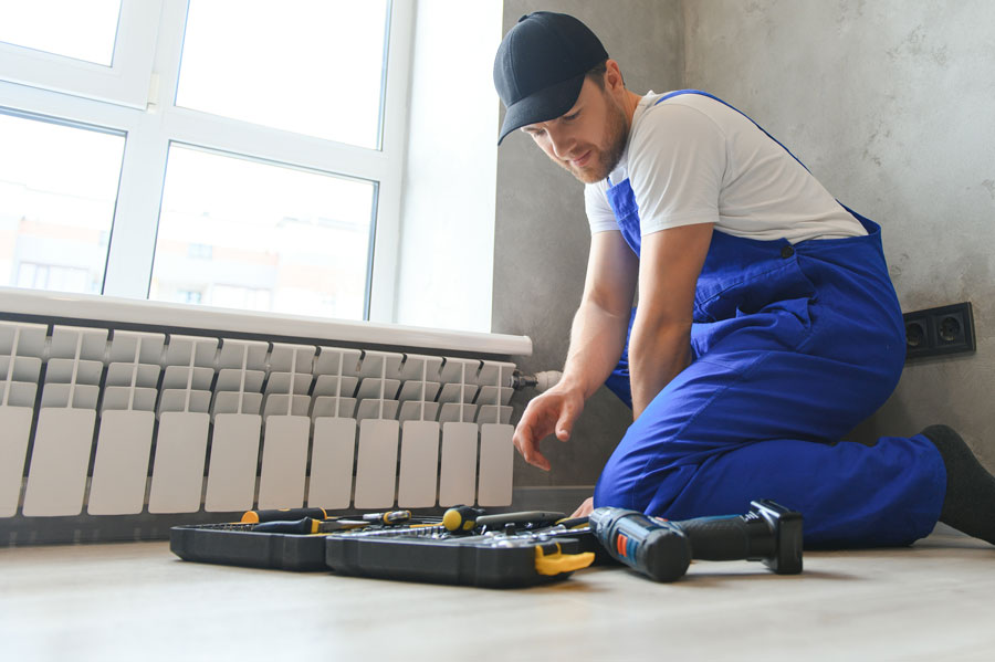 plombier fait la maintenance du radiateur avec ses outils désembouage entretien chauffage