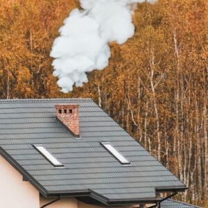 cheminée en fonctionnement dégage de la fumée blanche depuis le conduit sur le toit de la maison en forêt