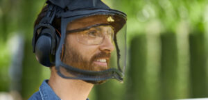 gros plan sur la tête du jardinier ou bûcheron qui porte des EPI tels que la visière de sécurité, le casque antibruit et les lunettes de protection