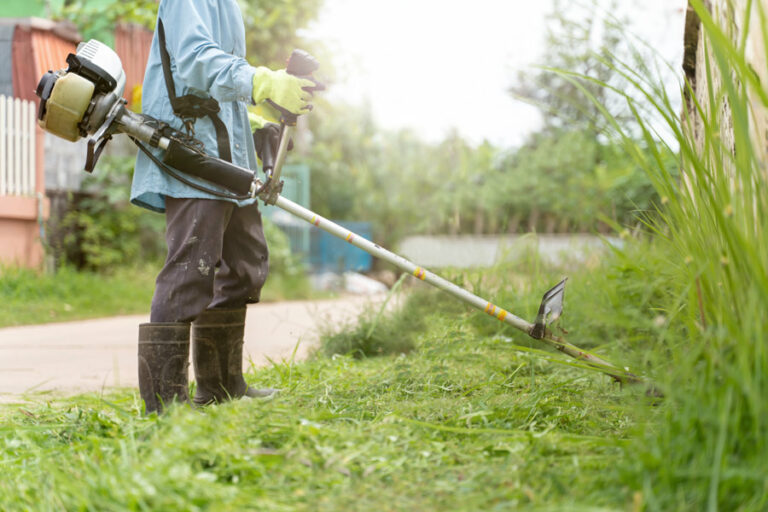 jardinier utilise la débroussailleuse pour entretenir le jardin