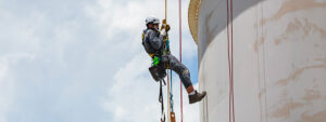 travailleur descend du toit du bâtiment en rappel avec un équipement de protection anti-chute pour sa sécurité : harnais, mousqueton et cordes