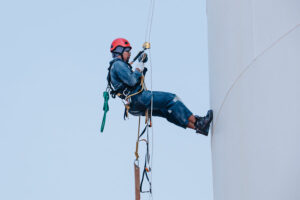 travailleur industriel travaille sur une citerne d'huile, le technicien fait la maintenance sur corde avec un harnais de protection sécurité anti-chute