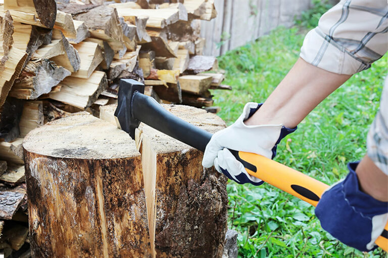 bûcheron qui porte des gants fend une buche de bois de chauffage avec une hache