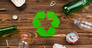 différents déchets recyclables posés sur une table en bois avec le logo du recyclage au milieu