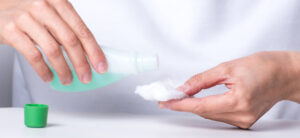 gros plan sur les mains de la femme qui fait couler du dissolvant sur un coton pour retirer son vernis à ongles