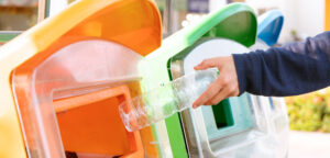 gros plan sur une main qui jette une bouteille de plastique dans la bonne poubelle de recyclage