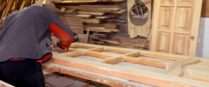 menuisier répare une porte de logement en bois dans son atelier de menuiserie