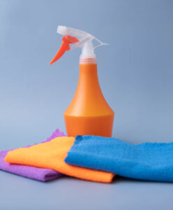 sur un fond bleu il y a des chiffons de nettoyage en microfibre de différentes couleurs disposés devant un pulvérisateur orange sur un fond bleu il y a des chiffons de nettoyage en microfibre de différentes couleurs disposés devant un pulvérisateur orange