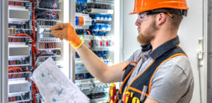 électricien professionnel travaille sur le tableau électrique industriel avec beaucoup de câbles et fusibles