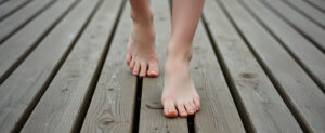 gros plan sur des pieds en train de marcher pieds nus sur la terrasse bois gros plan sur des pieds en train de marcher pieds nus sur la terrasse bois