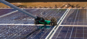 travailleur nettoyant les panneaux solaire photovoltaïques avec une brosse et de l'eau