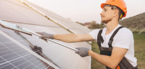 un technicien nettoie les panneaux solaires par une journée ensoleiillée