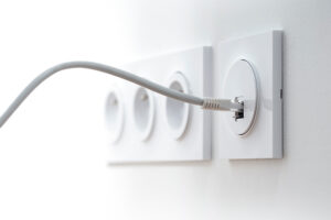 gros plan sur des prises électriques murales sur un mur blanc, un câble RJ45 est branché à la prise
