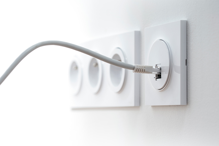 gros plan sur des prises électriques murales sur un mur blanc, un câble RJ45 est branché à la prise