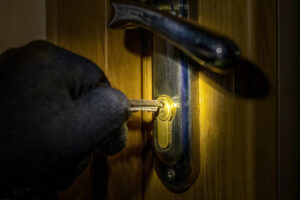 gros plan sur les mains gantées du cambrioleur qui ouvre la serrure de la porte avec une clé traffiquée pour bumper le cylindre