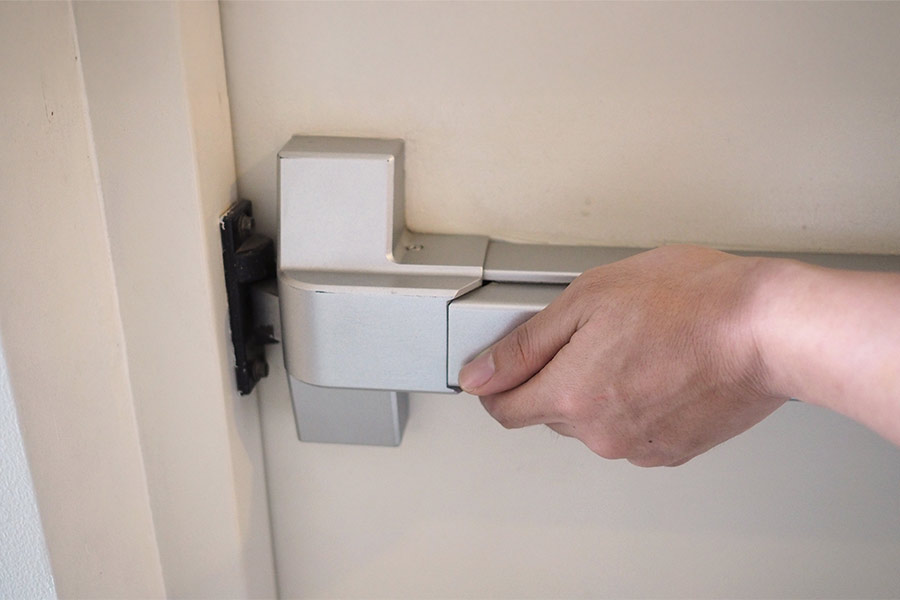 la main pousse la poignée de la porte coupe-feu de l'issue d'urgence pour l'évacuation incendie