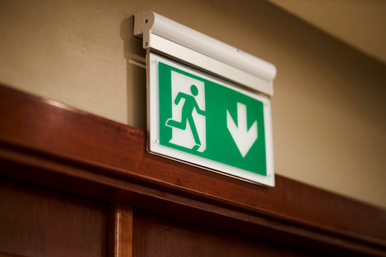 panneau issue de secours vert au-dessus de la porte de sortie d'urgence dans le bâtiment