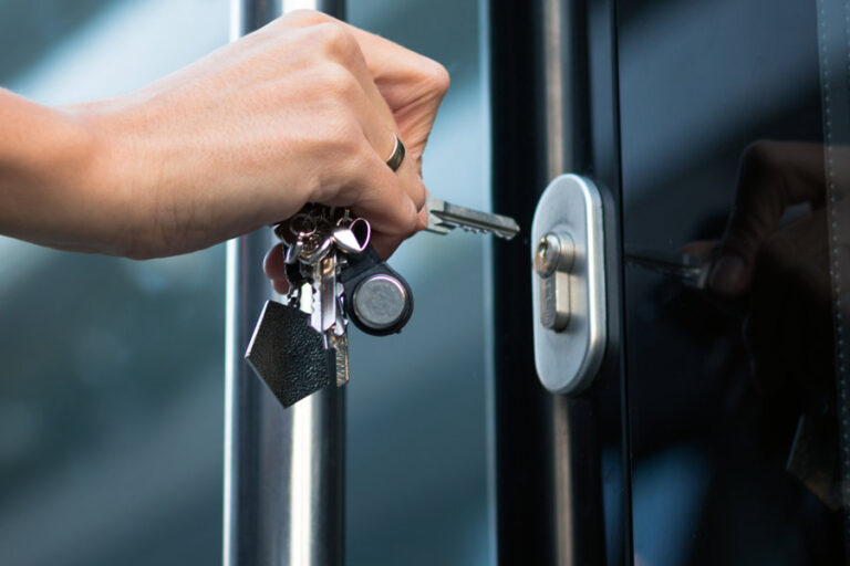 zoom sur la main d'une femme qui ouvre la porte d'entrée avec une clé à insérer dans le cylindre de la serrure