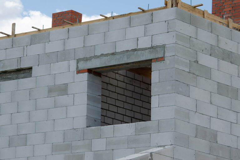 chantier de construction d'une maison. une ouverture dans les parpaings materialise l'embrasure de la fenêtre