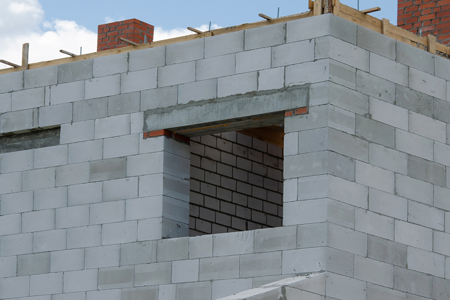 chantier de construction d'une maison. une ouverture dans les parpaings materialise l'embrasure de la fenêtre