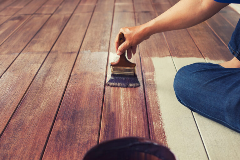 huiler le plancher de bois en appliquant au pinceau de l'huile teintée bois pour parquet