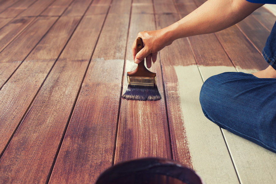 huiler le plancher de bois en appliquant au pinceau de l'huile teintée bois pour parquet
