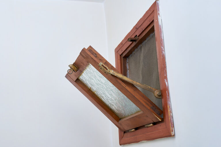 fenêtre à soufflet en bois ouverte sur un mur blanc