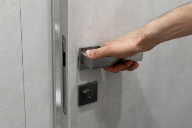 gros plan sur la main qui ouvre la porte en actionnant la poignée
