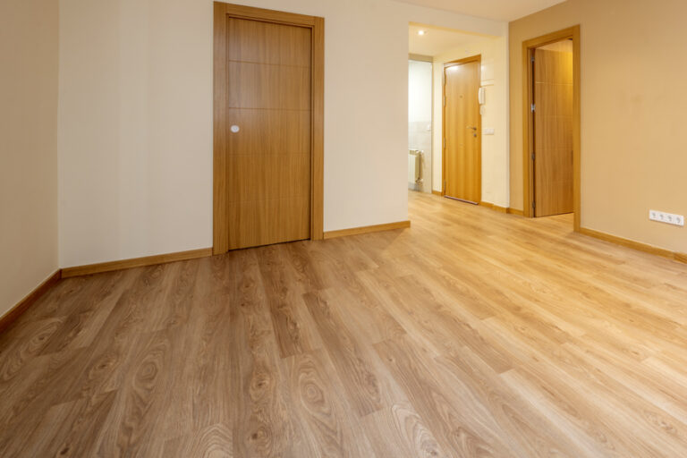 salon vide d'un appartement avec du parquet stratifié en chêne clair posé dans le sens de la largeur de la pièce