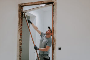 travailleur du bâtiment change le bâti de la porte intérieure sur le chantier de rénovation de maison