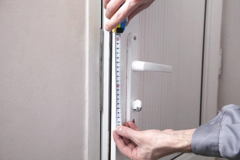 bricoleur mesure la dimension de la poignée de porte pour la remplacer avec une poignée de même entraxe