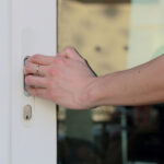 gros plan sur la main posée sur la poignée de la baie vitrée pour ouvrir la porte