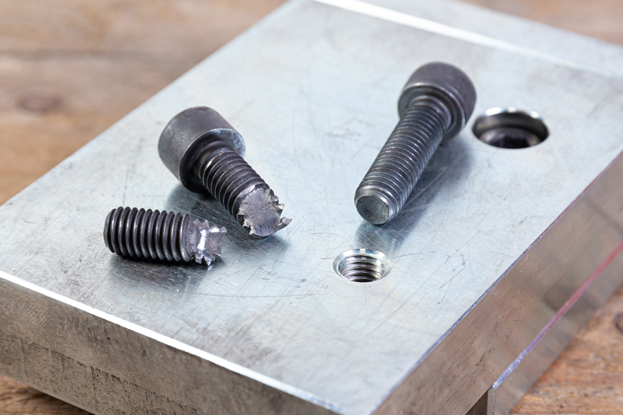 boulons posés sur un morceau de métal un boulon est cassé l'autre est entier