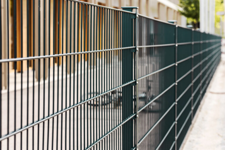 clôture de la propriété privée en treillis ou grillage rigide fixée sur des poteaux et platines sur une dalle béton